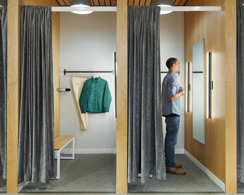 Man standing in a modern clothing store with wooden walls and ceiling, looking at a jacket on a rack.