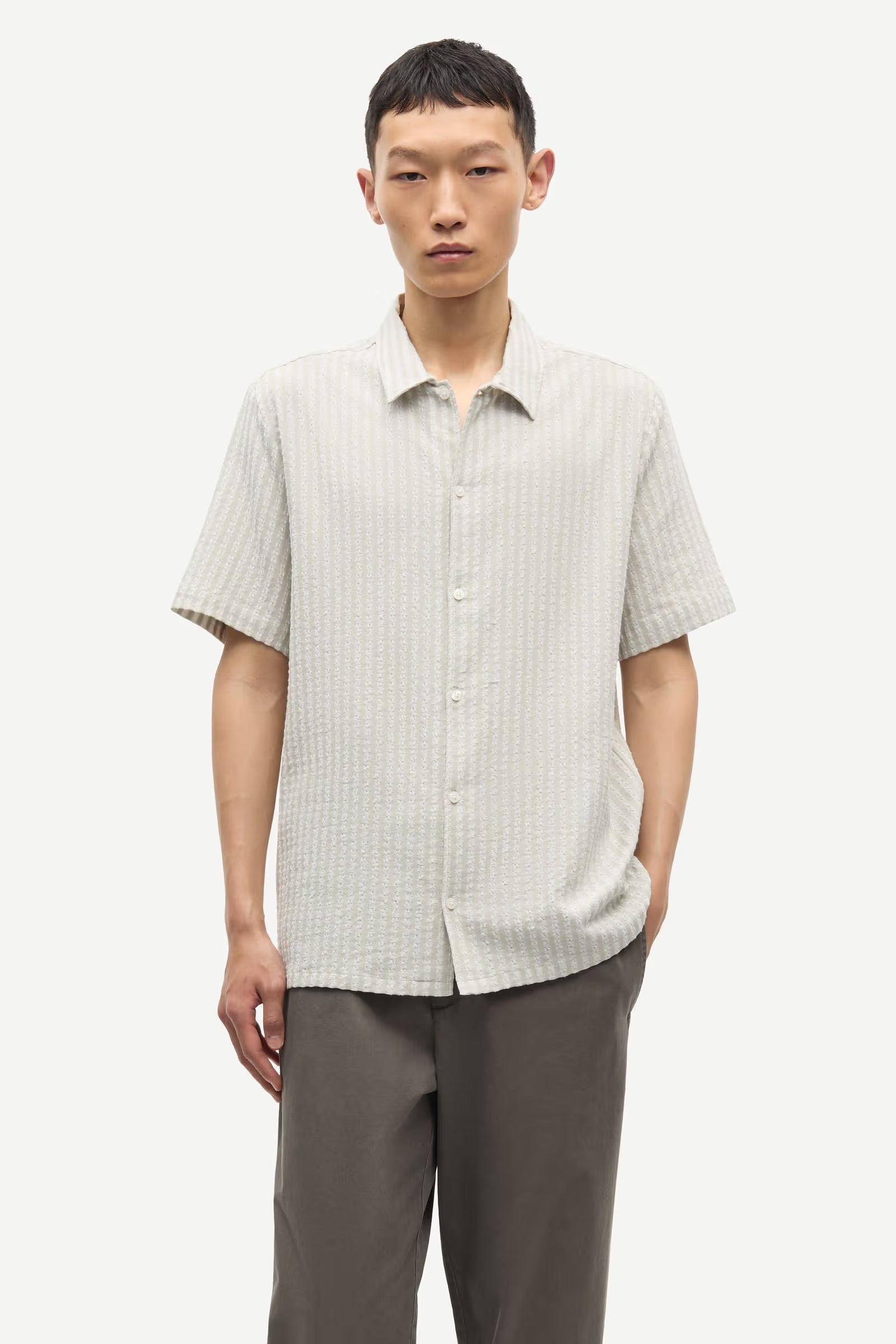 Jaxen Grey Man wearing a light-colored checkered shirt and gray pants on a white background