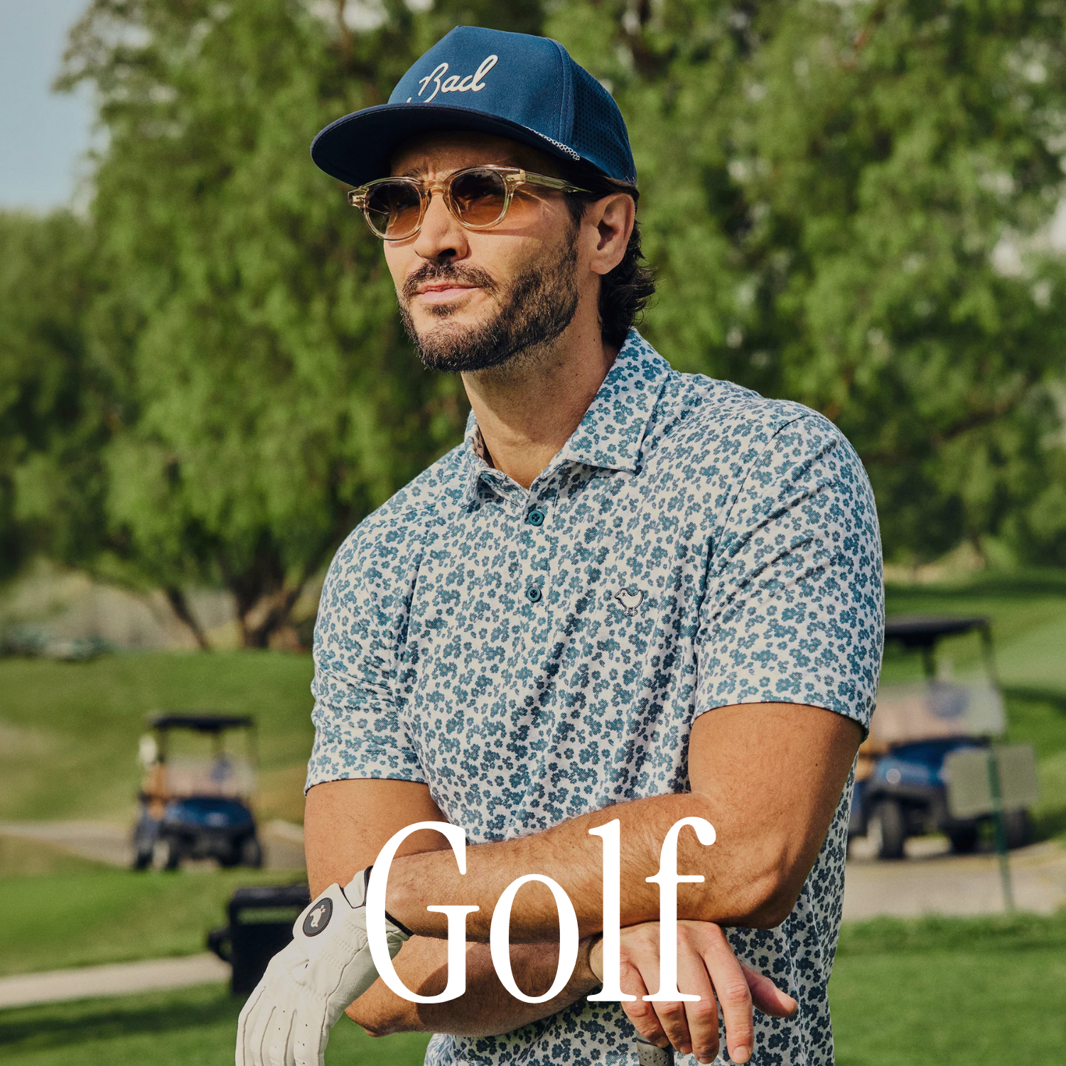Man on a golf course wearing a blue cap and sunglasses, holding a golf club. Category title "Golf"